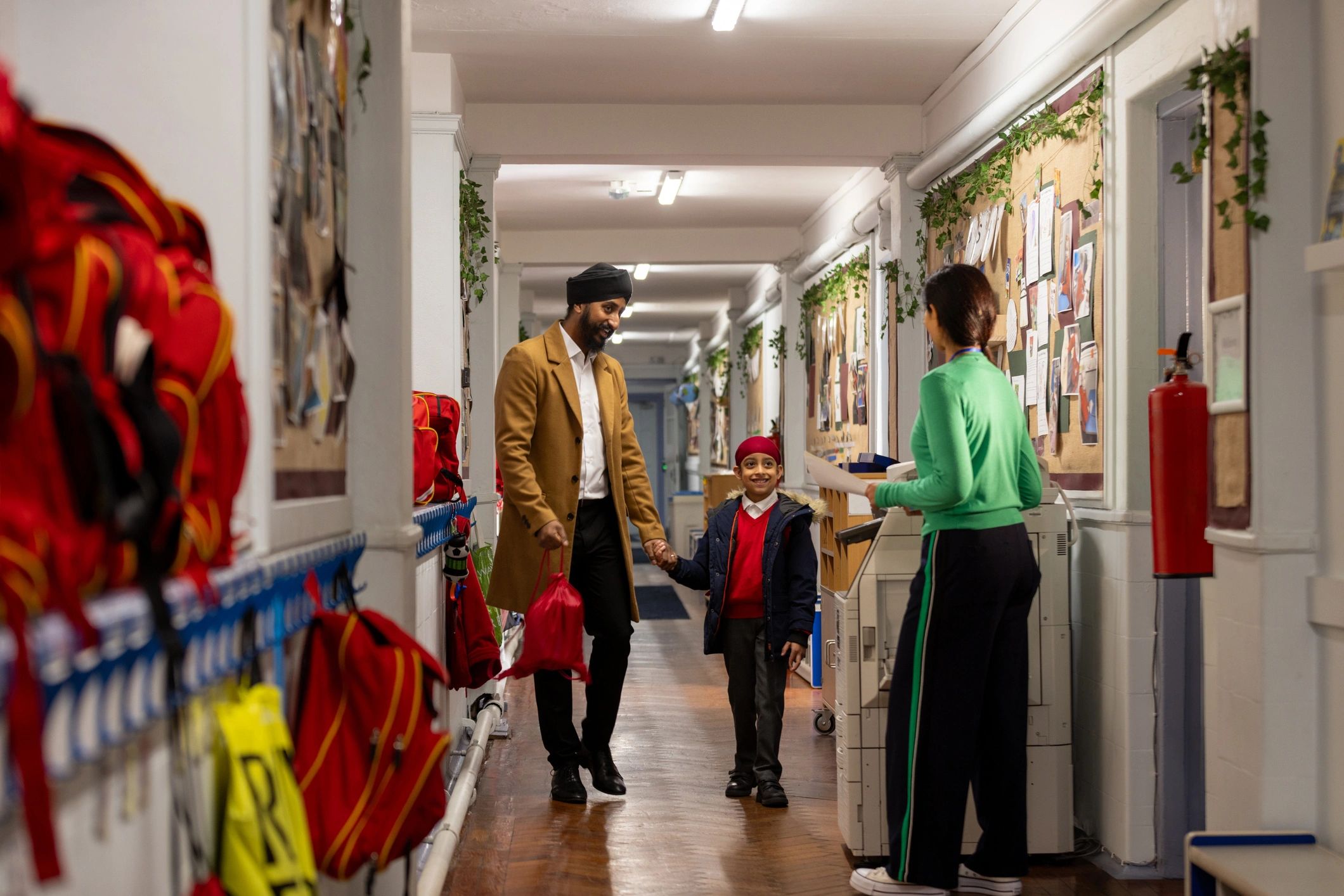 Parent and child meeting a teacher in an elementary school hallway